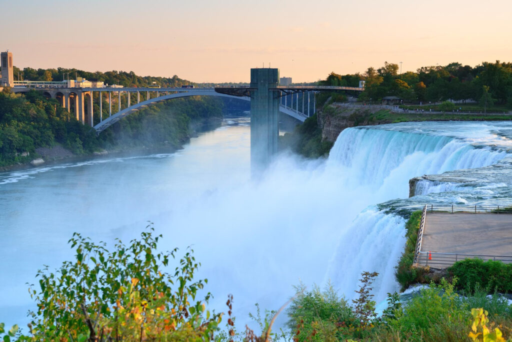 Majestic Niagara Falls with mist rising and bridge connecting Canada and U.S.
