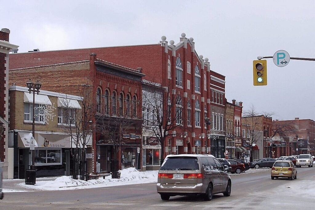 Busy snowy downtown street with historic buildings and cars driving by.