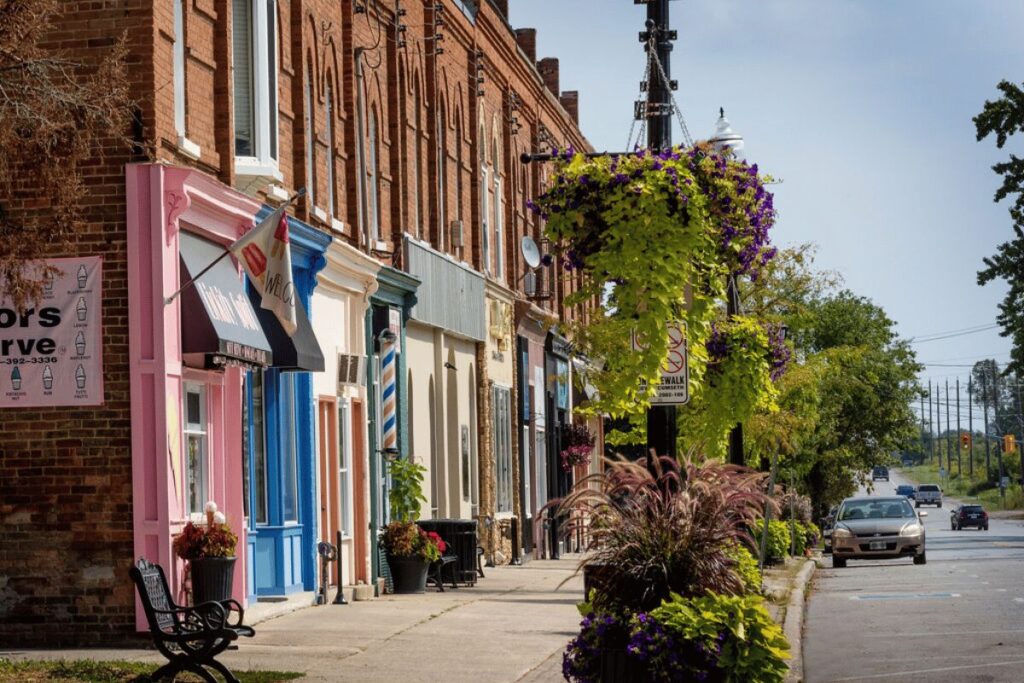 Sidewalk view of vibrant storefronts and flower baskets on New Tecumseth’s main street.