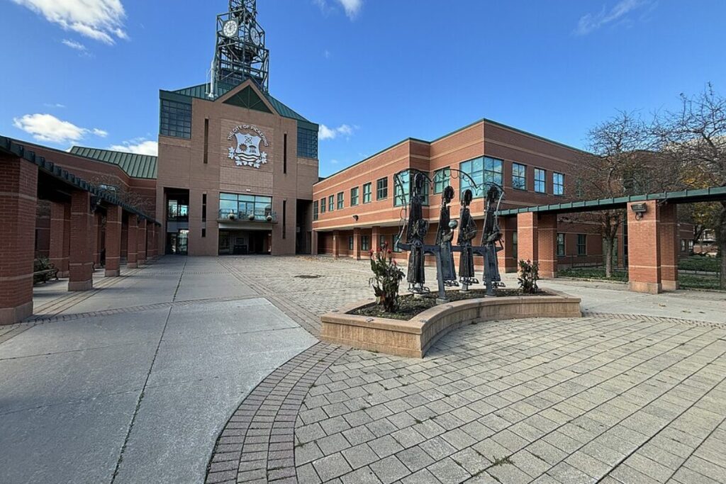 Civic centre in Pickering with statues, clock tower, and blue sky.